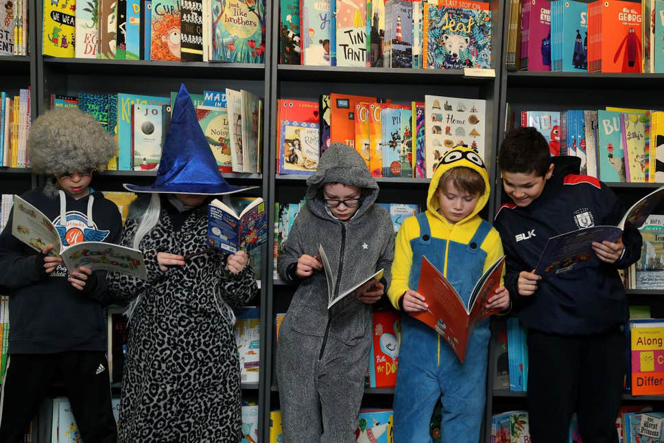 pupils in costumes reading books